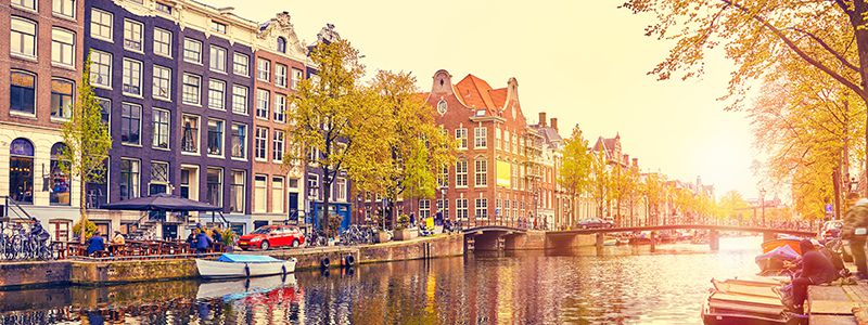 Amsterdam i solljus med sina broar och kanaler.